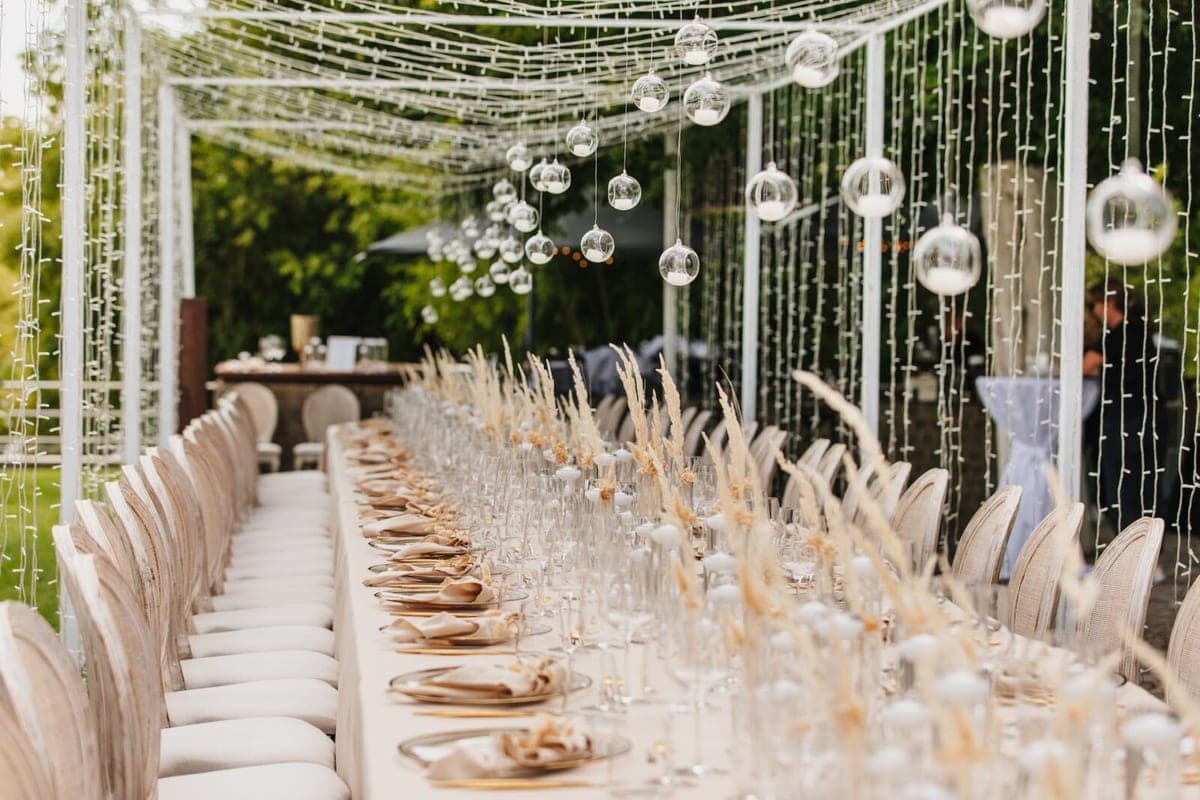 Hochzeitstisch im Freien mit Pampasgras, Glasgloben und Lichterketten