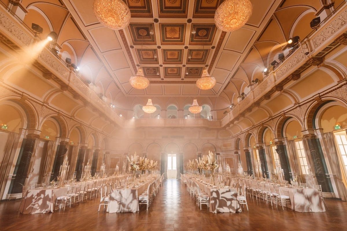 Prunkvoller Hochzeitssaal mit festlicher Tischdekoration, goldenen Kerzenständern und Kronleuchtern