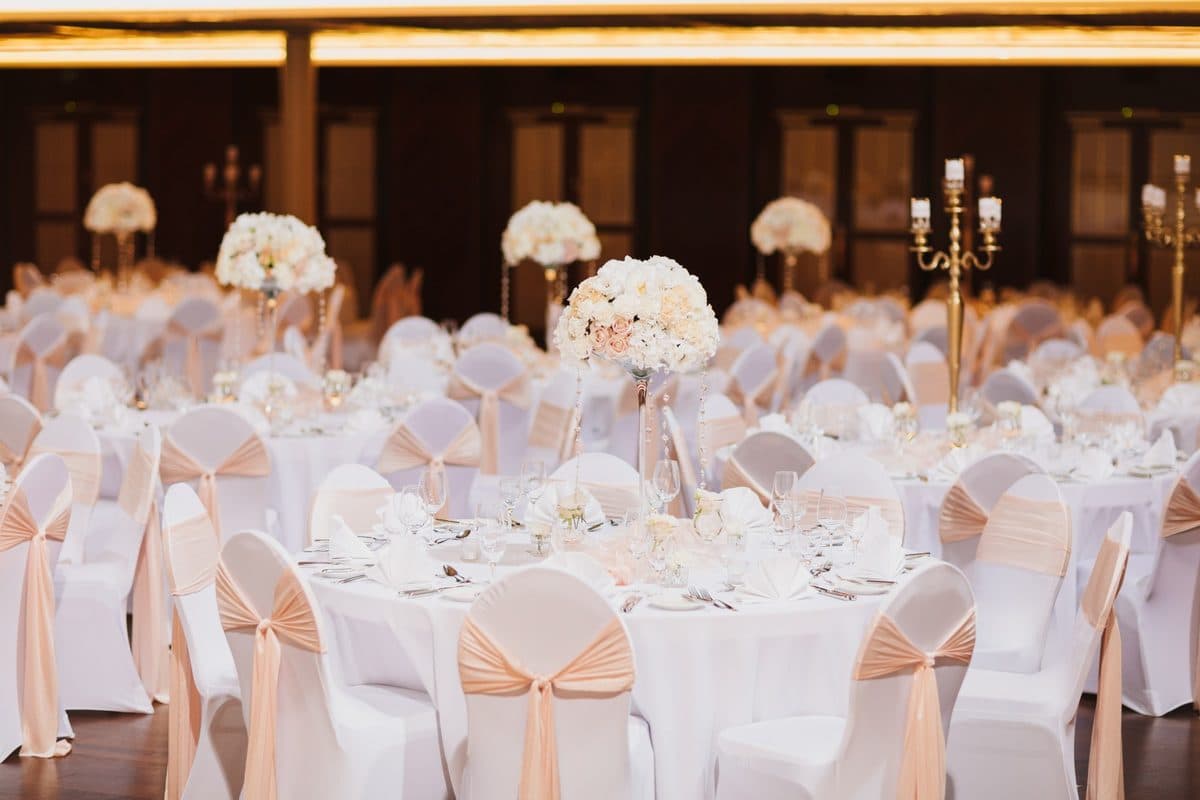 Bénazetsaal im Kurhaus Baden-Baden mit hohen Blumengestecken auf Martiniglas-Vasen, Kristallanhängern und rosé-fliederfarbenen Stuhlschleifen