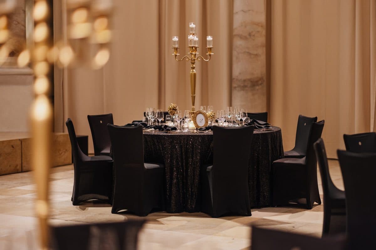 Festlich gedeckte Tafel in Schwarz und Gold mit hohem Kerzenleuchter