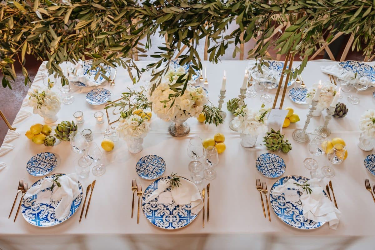 Detailaufnahme der Olivenzweig-Tafel mit Kerzen, Blumen und Artischocken
