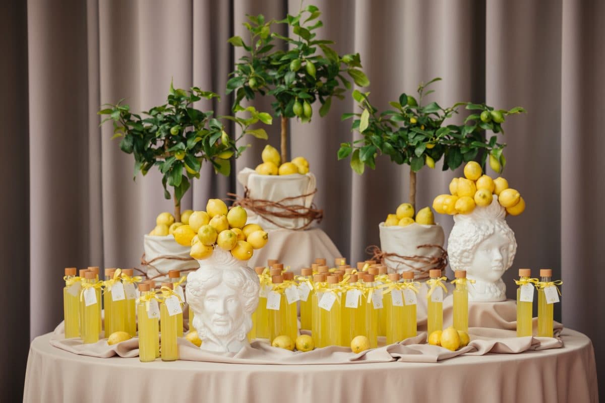 Gastgeschenke-Tisch mit Limoncello-Fläschchen, Zitronenbäumchen und Keramikköpfen