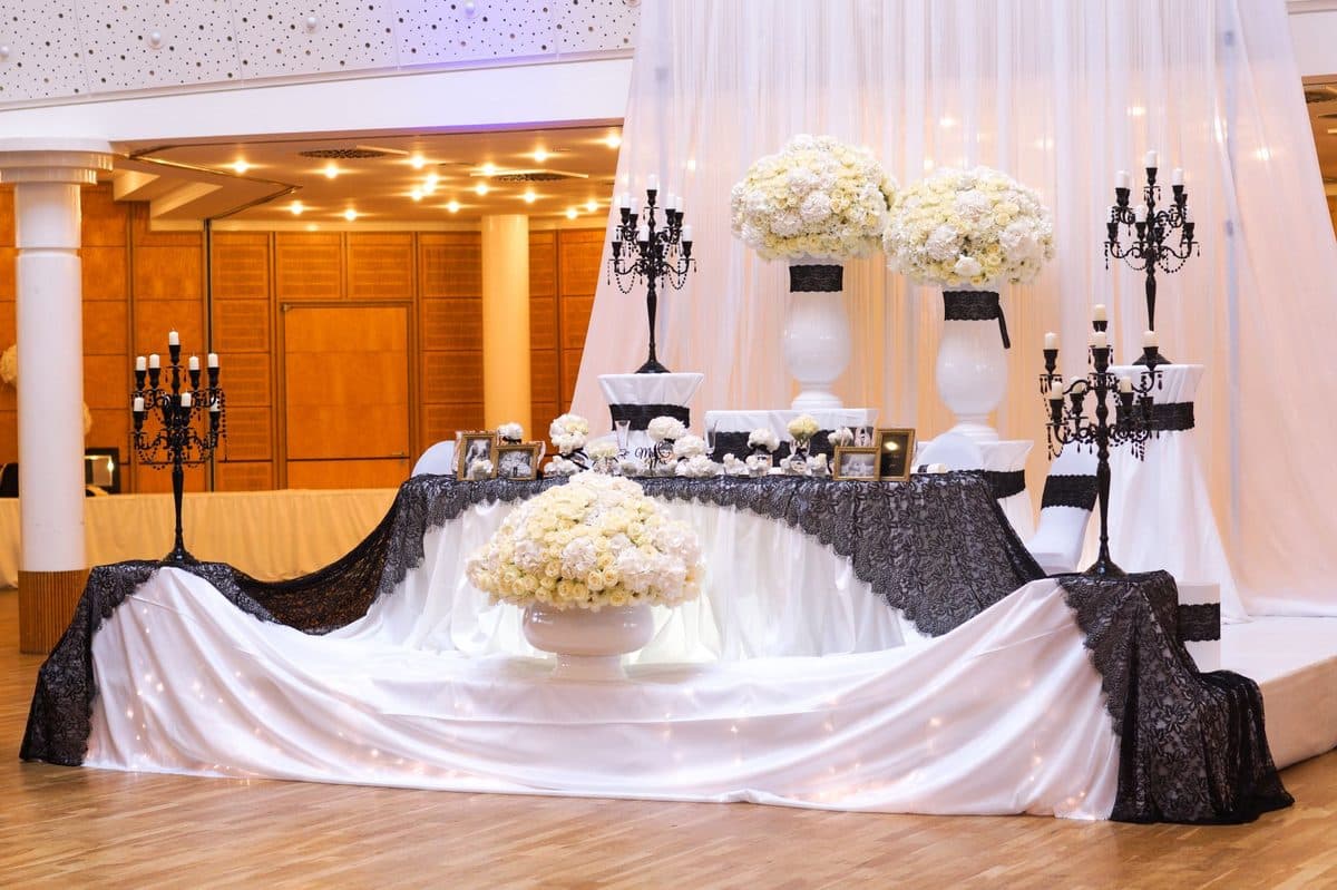 Brauttisch in Schwarz-Weiß mit Spitzenstoff, weißen Blumenkugeln und schwarzen Kerzenleuchtern