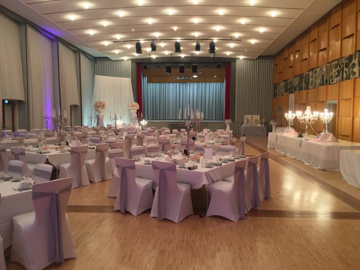 Festsaal mit Bühne, flieder Stuhlhussen und Kristall-Kerzenständern