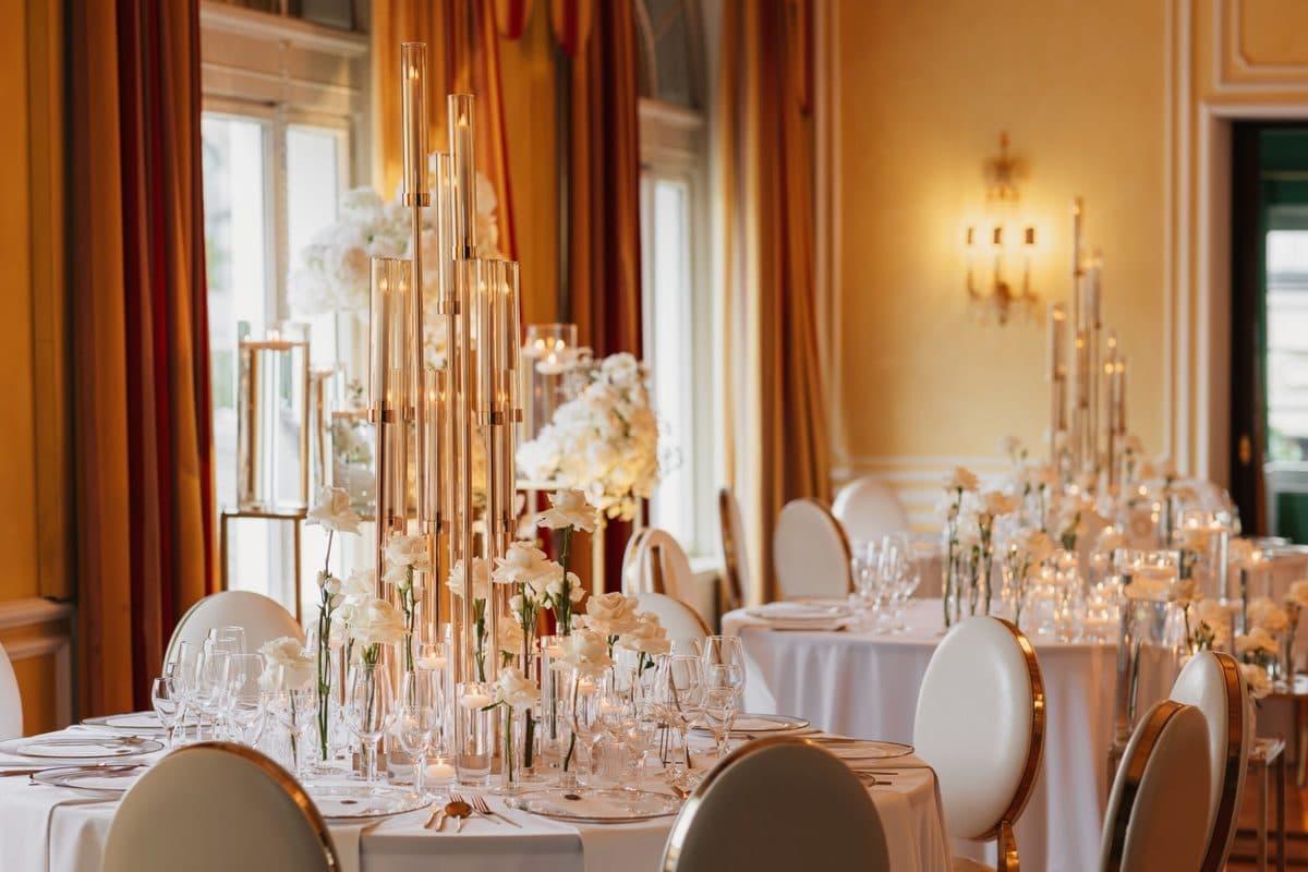 Detailaufnahme goldener Glas-Kerzensäulen mit weißen Rosen und Teelichtern