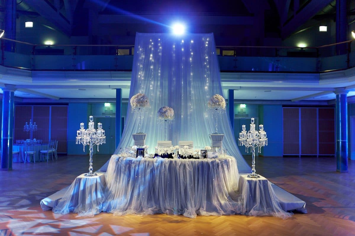 Brauttisch unter Lichter-Baldachin mit Kristall-Kerzenständern und weißen Blumenkugeln