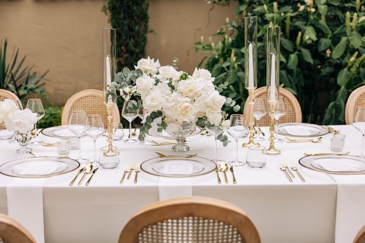 Detailaufnahme Tischdeko mit goldenen Kerzenständern, weißen Rosen und Eukalyptus