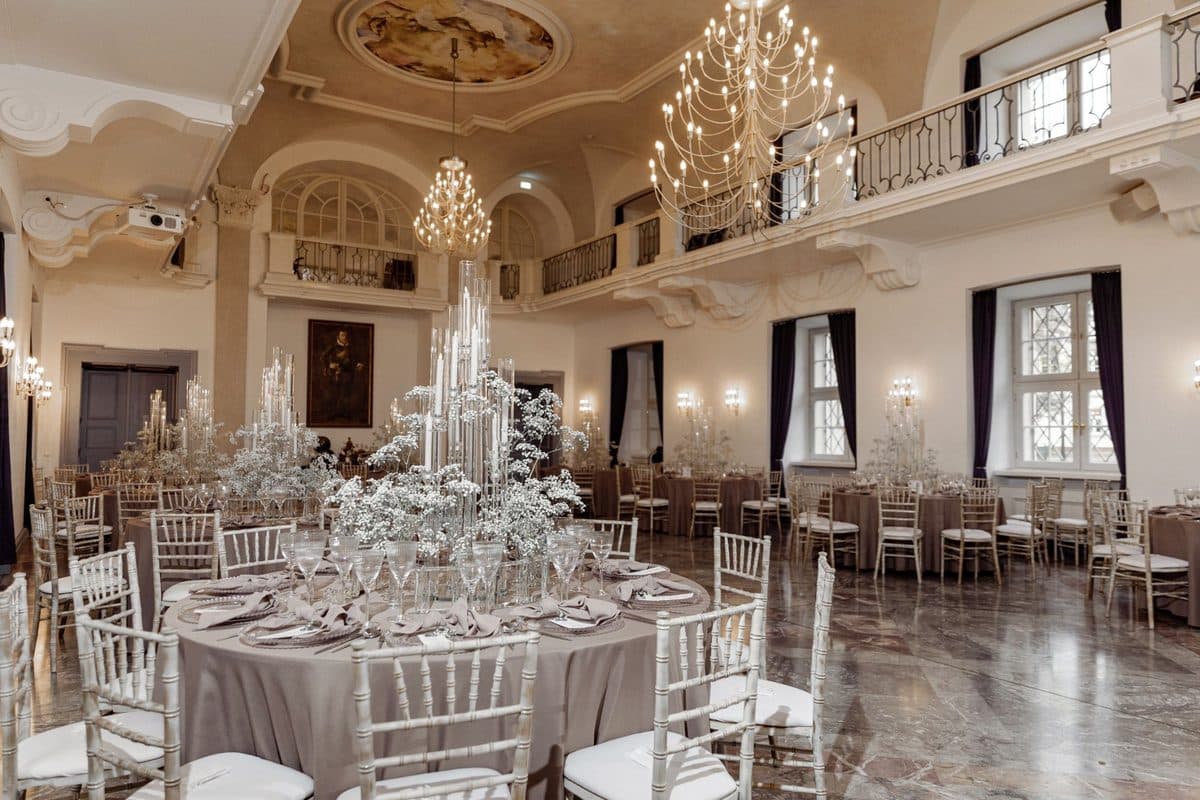 Festsaal mit Deckenfresko, Galerie und runden Tischen in Taupe mit hohen Kristall-Kerzensäulen