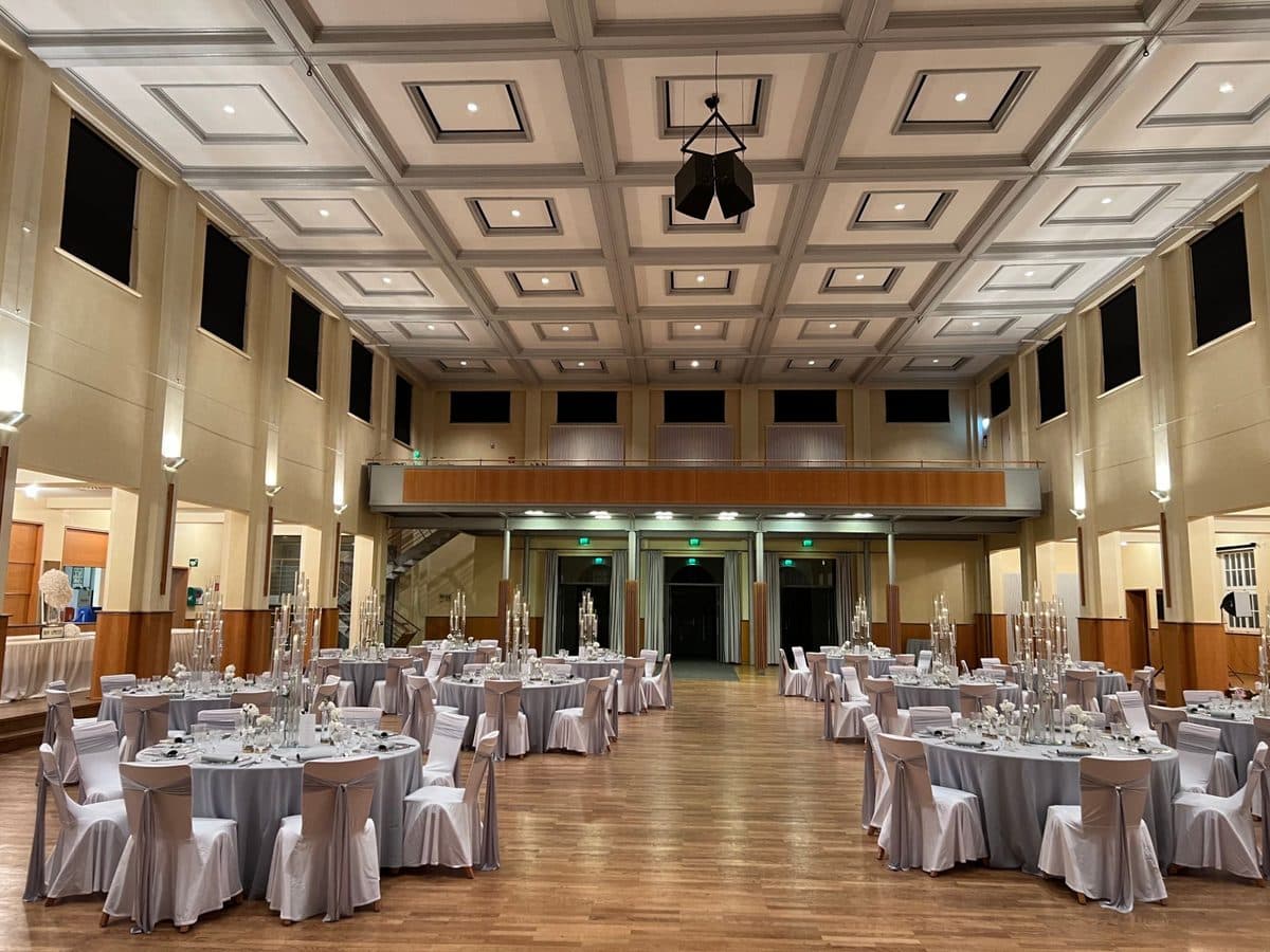 Festsaal der Stadthalle Haslach mit Galerie und runden Hochzeitstischen in Hellgrau mit hohen Kristall-Kerzensäulen
